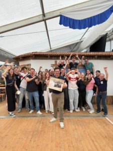 Gruppenfoto der Stadtkapelle Wernau, die stolz eine Auszeichnung präsentiert. Die Musiker und Unterstützer stehen in einem festlichen Zelt und feiern gemeinsam. Das Bild spricht Musikliebhaber im Raum Esslingen und Stuttgart an und zeigt die Gemeinschaft und Begeisterung für musikalische Themen.