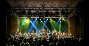 "Stadtkapelle Wernau bei einem Live-Konzert, unter der Leitung des Dirigenten, mit strahlenden Lichtern und einer engagierten Zuschauerreihe. Attraktive Darstellung der musikalischen Vielfalt im Landkreis Esslingen und Stuttgart."