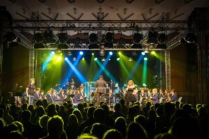 Auftritt der Stadtkapelle Wernau mit Musiker:innen vor einem begeisterten Publikum, beleuchtet von bunten Scheinwerfern, in einem Veranstaltungssaal. Ideal für Musikliebhaber und Interessierte aus Esslingen und Stuttgart.