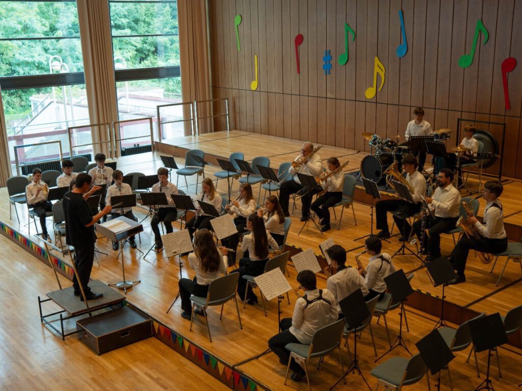 Proben der Stadtkapelle Wernau mit Musikern im Alter von 10 bis 20 Jahren, die in einem modernen Probenraum spielen. Die Szene zeigt das Orchester während einer Probe in einem lichtdurchfluteten Raum, ideal für Musikliebhaber und potenzielle Mitglieder im Raum Esslingen und Stuttgart.