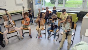 Kinder der Stadtkapelle Wernau üben das Musizieren in einer Gruppenstunde, während sie Musikhelfer halten. Die Szene vermittelt Gemeinschaft und Freude an der Musik und spricht Musiker und Musikliebhaber im Raum Esslingen und Stuttgart an.