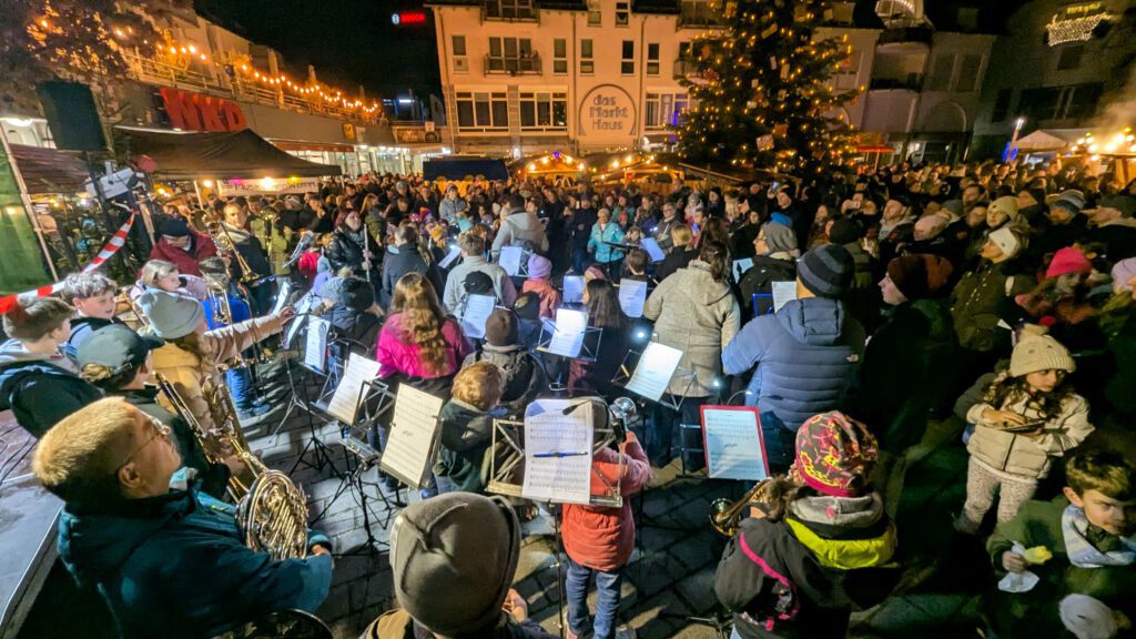 Musiker der Stadtkapelle Wernau treten bei einem Weihnachtskonzert in der Innenstadt auf, umgeben von begeisterten Zuschauern. Die Veranstaltung zieht Musikliebhaber aus der Region Esslingen und Stuttgart an und fördert die Gemeinschaft durch musikalische Darbietungen.