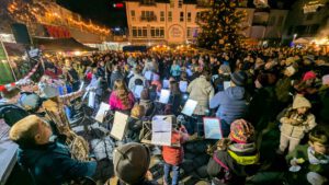 Musiker der Stadtkapelle Wernau treten bei einem Weihnachtskonzert in der Innenstadt auf, umgeben von begeisterten Zuschauern. Die Veranstaltung zieht Musikliebhaber aus der Region Esslingen und Stuttgart an und fördert die Gemeinschaft durch musikalische Darbietungen.