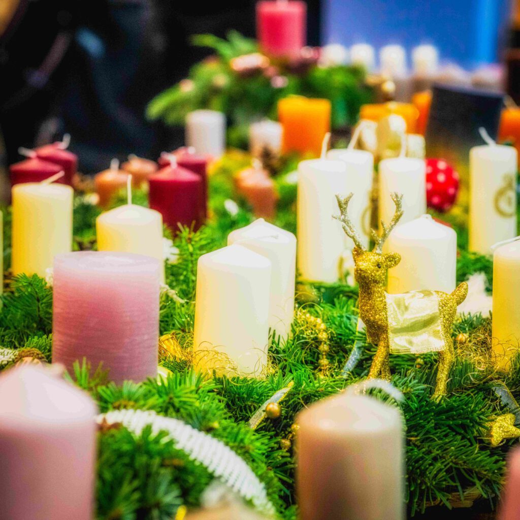 Festliche Weihnachtsdekoration mit bunten Kerzen und einem goldenen Rentier in einem Adventskranz, ideal zur Ansprache von Musikern und Musikliebhabern im Raum Esslingen und Stuttgart.