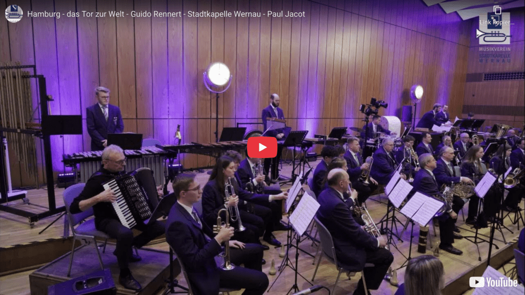 Stadtkapelle Wernau bei einem Auftritt, Musiker spielen verschiedene Instrumente in einem modernen Konzertsaal, umgeben von Lichtern. Ideal für Musikliebhaber in Esslingen und Stuttgart.