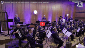 Stadtkapelle Wernau bei einem Auftritt, Musiker spielen verschiedene Instrumente in einem modernen Konzertsaal, umgeben von Lichtern. Ideal für Musikliebhaber in Esslingen und Stuttgart.