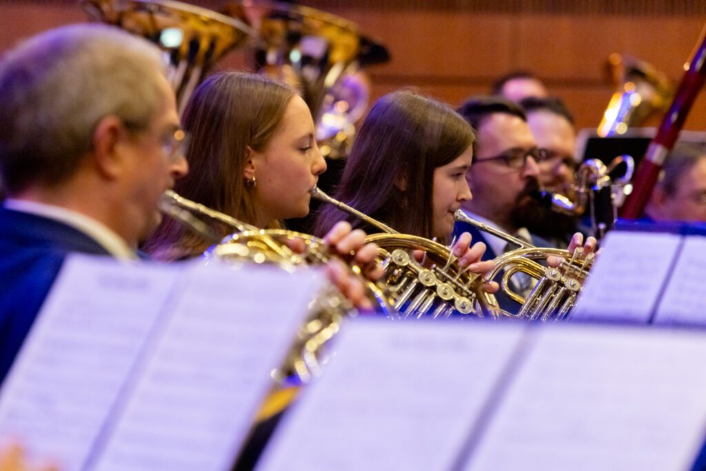 Stadtkapelle Wernau: Musiker spielen Hörner in einem Konzertsaal, umrahmt von Notenblättern. Ansprechende Musik für Liebhaber im Raum Esslingen und Stuttgart.