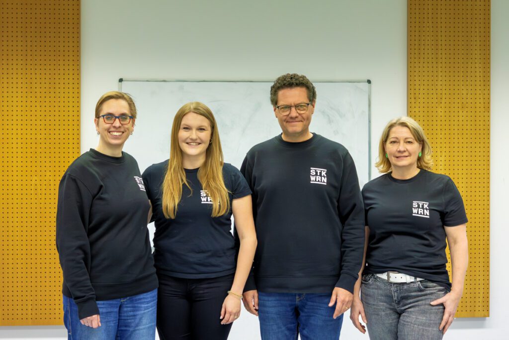 Mitglieder der Stadtkapelle Wernau in einheitlichen Sweatshirts, die Musikliebhaber und Musiker im Raum Esslingen und Stuttgart ansprechen. Die Aufnahme zeigt ein engagiertes Team, das sich für musikalische Aktivitäten und Gemeinschaft einsetzt.