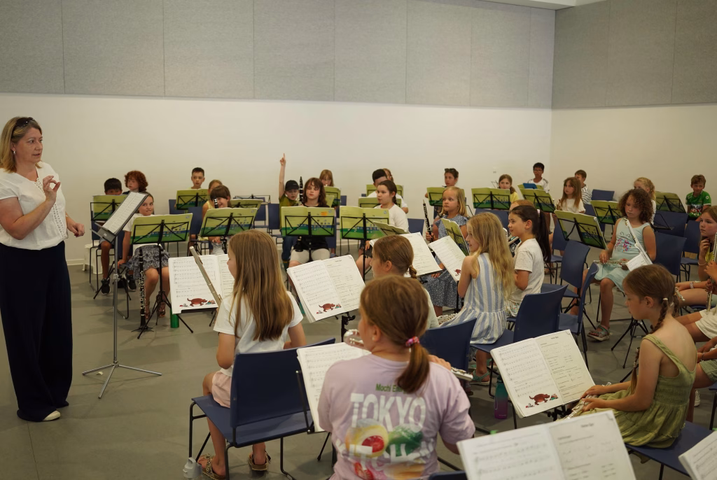 Proben der Stadtkapelle Wernau mit jungen Musikern im Raum Esslingen und Stuttgart. Die Kinder spielen verschiedene Instrumente und folgen der Anleitung einer Dirigentin. Ideal für Musikliebhaber und Interessierte an musikalischen Aktivitäten in der Region.